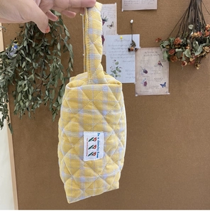 Close-up of quilted cotton handbag with yellow and purple checkered pattern and floral label