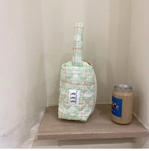 Detail of green checkered quilted handbag with tulip label on a wooden shelf