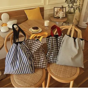 Détail de divers sacs fourre-tout en toile à rayures et carreaux dans un café