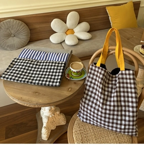 Gros plan de sacs cabas en toile à rayures et carreaux posés sur une table en bois