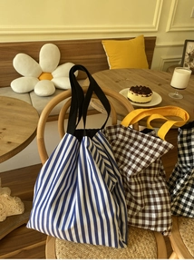 Détail de sacs cabas en toile à rayures et carreaux sur une chaise en bois