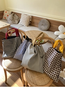 Quatre grands sacs cabas en toile à rayures et carreaux sur une chaise en bois
