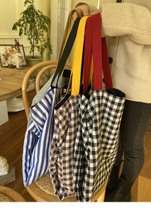 Détail de grands sacs cabas en toile à rayures et carreaux avec des poignées contrastées