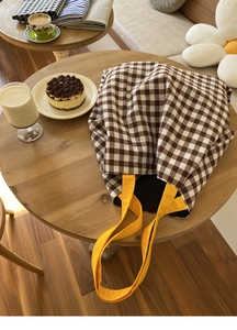 Détail d'un sac cabas à carreaux avec anses jaunes dans un cadre de café chaleureux