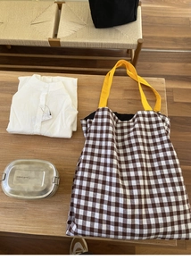 Détail d'un sac cabas en toile à carreaux avec poignées jaunes sur table en bois