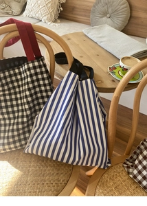 Gros plan de sacs cabas en toile à rayures et carreaux suspendus sur une chaise en bois