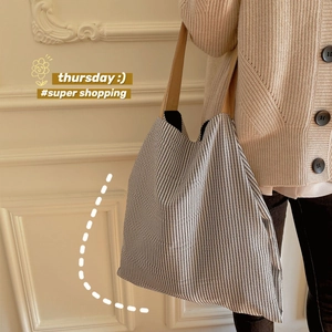 Sac cabas minimaliste en toile à rayures noires et blanches porté par un mannequin chic