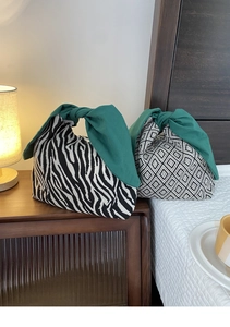 Dettaglio di borse bento in tela con motivi a zebra e manici a fiocco verde scuro