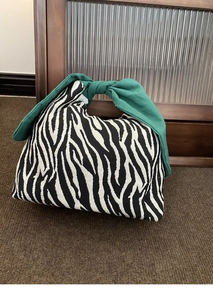 Dettaglio della borsa bento zebrata con un elegante manico annodato verde