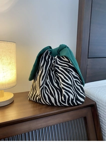 Borsa bento motivo zebra con grande fiocco verde come manico su un comodino elegante