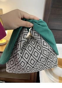 Dettaglio borsa bento in tela con motivo a rombi bianchi e neri e manico a nodo verde