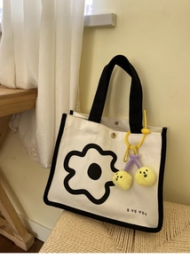 Détail du sac à lunch en toile blanche avec imprimé tournesol noir et breloque cerise