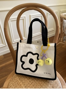 Détail d'un sac repas en toile avec imprimé fleuri noir et porte-clé cerise jaune