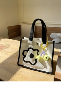 Détail du sac à lunch en toile avec imprimé floral et breloque cerise sur table en bois