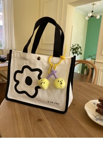 Détail du sac à lunch en toile avec motif floral noir et pendentif cerise jaune