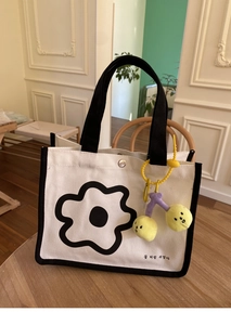 Détail du sac lunch en toile avec motif floral minimaliste et breloque cerise en peluche