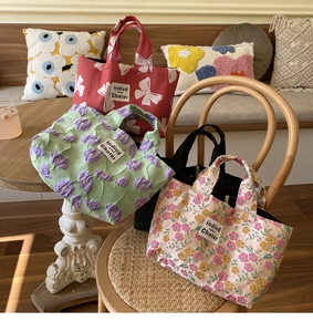 Three canvas tote bags with bows and floral embroidery on a wooden table setup