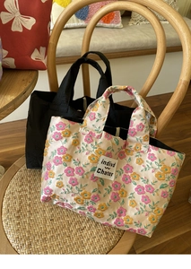 Detail of floral embroidery and black handbags on a wooden chair in a cozy setting