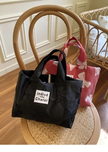 Close-up of the bow embroidery detail and brand label on fabric tote bags