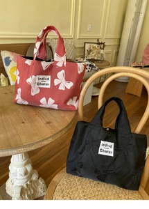 Detail of red and black canvas tote bags with bow patterns on a vintage wooden chair