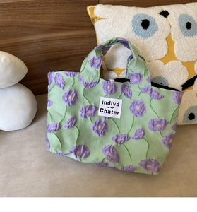 Close-up of floral seersucker handbag with purple flowers and white branded label