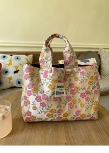 Close-up of floral embroidery on beige satin fabric with brand tag on small tote bag