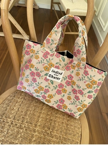 Floral canvas handbag detail showing small pink flowers and retro woven chair background