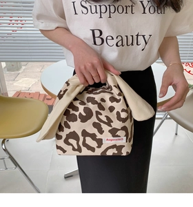 Close-up of leopard print canvas tote bag with rabbit ear handles and snap button closure