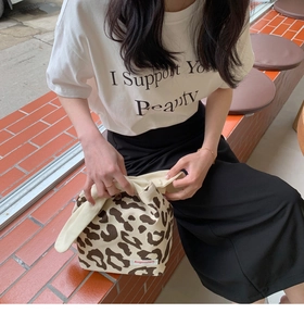 Close-up of leopard print canvas tote bag with knotted handles and brand patch detail