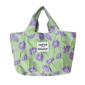 Front view of green floral handbag with purple poppy pattern and pleated texture