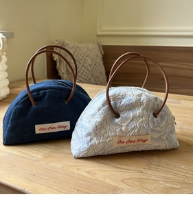 Detail of denim and floral jacquard semicircular handbags with round handles