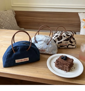 Semicircular mini handbags in denim and jacquard textures on a cozy cafe table setting