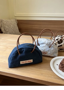 Detailed view of semi-circular denim and cow print handbags with brown round handles