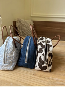 Three mini pouches in denim, floral, and cow print with round leather handles and zippers