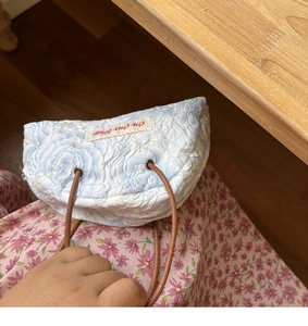 Detail of floral quilted crescent handbag with rope handle and On Our Way tag