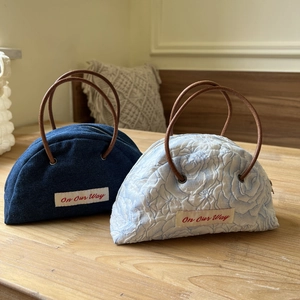 Retro denim and floral semicircular handbags with On Our Way labels on wood table