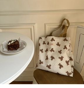 Detail of embossed bear pattern and Sonder label on creamy quilted tote bag texture