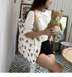 Detail of white tote bag with bear print and textured bubble fabric shown on shoulder