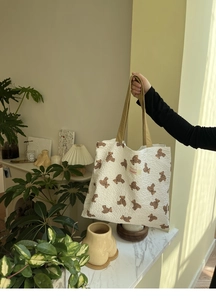 Detail of white quilted tote bag with brown bear pattern and Sonder logo tag