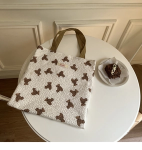 Detail of white embossed tote bag with brown teddy bear patterns and Sonder cloth label