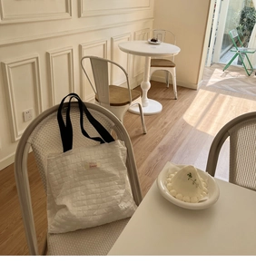 Detail of white puffer tote bag with embossed grid texture and black wide shoulder strap