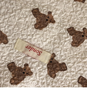 Detail of seersucker fabric texture with brown bear pattern and Sonder brand label