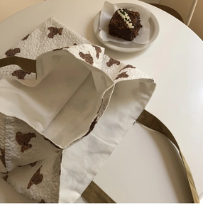 Detail of white seersucker tote bag with brown bear patterns and pleated texture