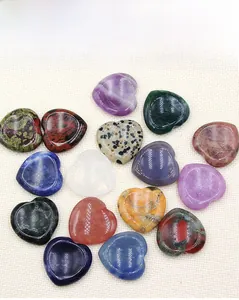 Flat lay of multiple polished 30mm heart-shaped natural crystal stones on fabric
