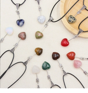 Macro detail of various natural agate crystal heart pendants with Cupid arrow design