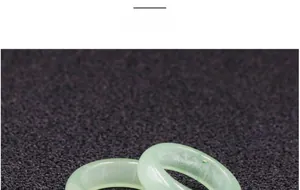 Macro shot of two overlapping light green natural jade rings on a textured background