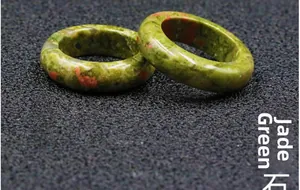 Macro shot of two polished Unakite rings with natural green and orange mossy patterns
