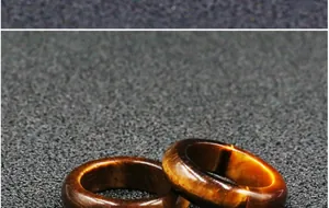 Close-up of two polished natural tiger eye stone rings with golden brown fibrous texture