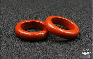 Macro shot of two polished red amber rings overlapping on a textured gray background