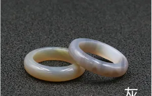 Detail shot of grey and beige translucent agate gemstone rings on a textured background